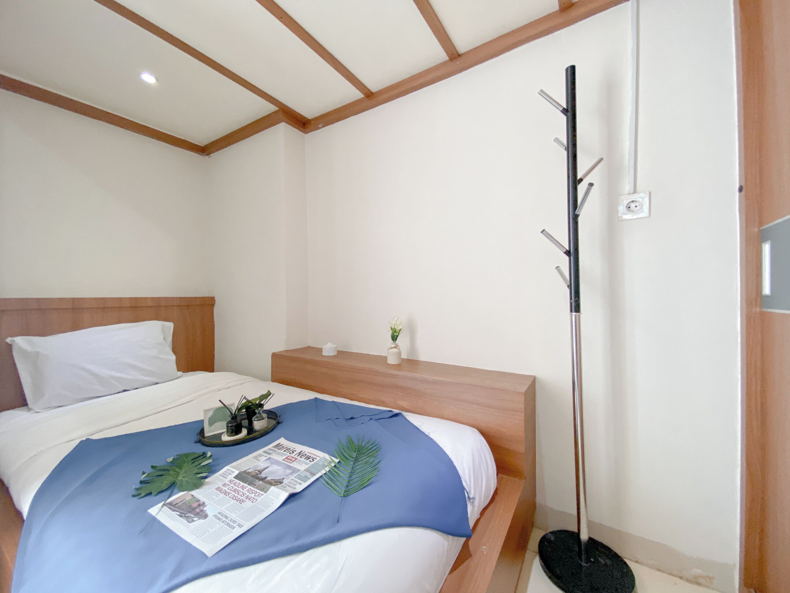 A bedroom with a bed, a nightstand, a floor lamp, and a small table with a plant.