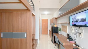 Une cuisine moderne avec des meubles en bois, un four encastré et un téléviseur à écran plat fixé au mur.
