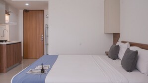 Una habitación de hotel con una cama, una mesita de noche, una lámpara y una puerta de madera.