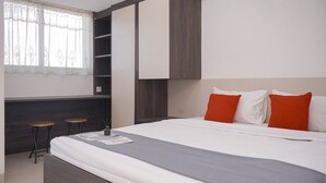 A modern hotel room with a large bed, a built-in wardrobe, and a small seating area with stools. - Brand New and Cozy Studio Apartment at Cisauk Point (Cisauk)