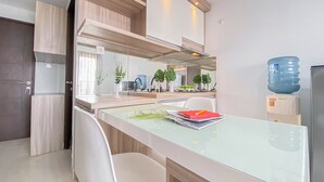 Una cucina moderna con tavolo da pranzo in vetro, sedie bianche, mobili in legno e un distributore di acqua.