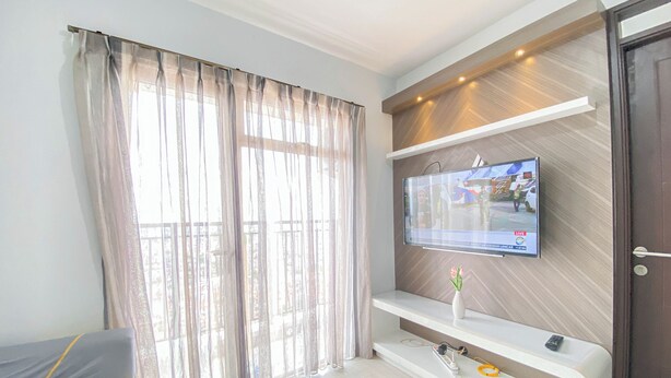 Un soggiorno moderno con una televisione grande montata su una parete in legno, un divano e una finestra coperta da tende.