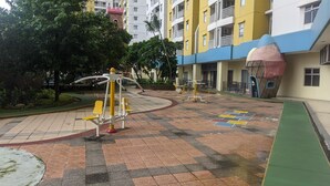 An outdoor exercise area with fitness equipment, surrounded by a courtyard with a tiled floor and greenery. - Warm and Minimalist Studio (No Kitchen) at Great Western Apartment (Tangerang)