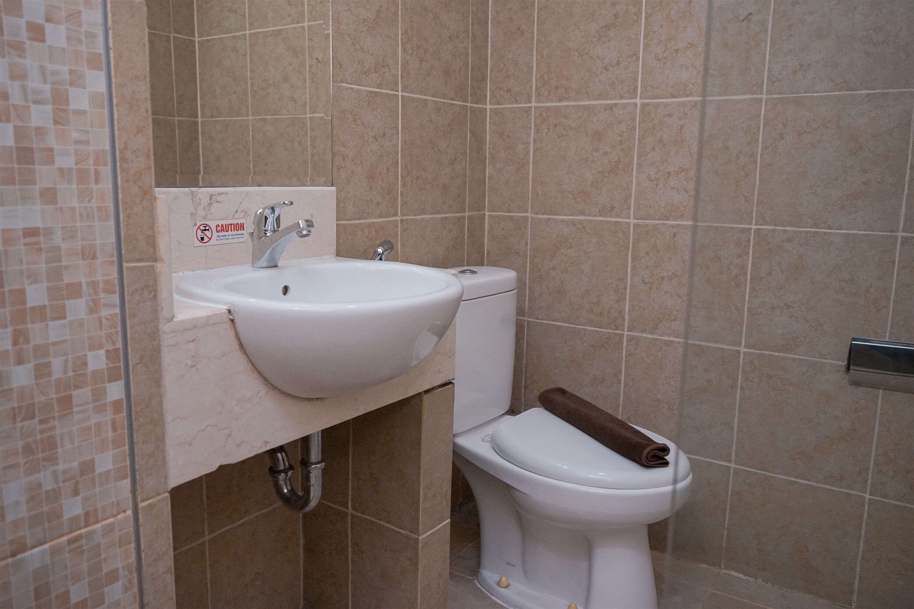 A bathroom with a sink, toilet, and a caution sign on the wall.