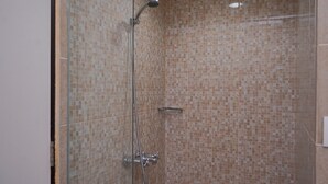 A shower with a glass door, tiled walls, and a handheld showerhead. - Warm and Minimalist Studio (No Kitchen) at Great Western Apartment (Tangerang)