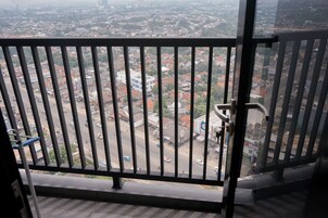 Un balcón con barandilla metálica que da a una vista urbana con edificios y calles.