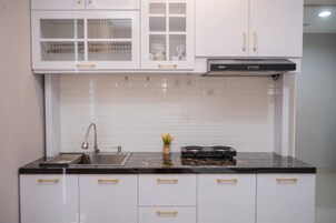Cocina moderna con armarios blancos, encimera negra y pileta de acero inoxidable.