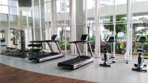 A gym with treadmills, dumbbells, and exercise machines. - Cozy Studio Apartment at Casa De Parco near ICE BSD (Pagedangan)
