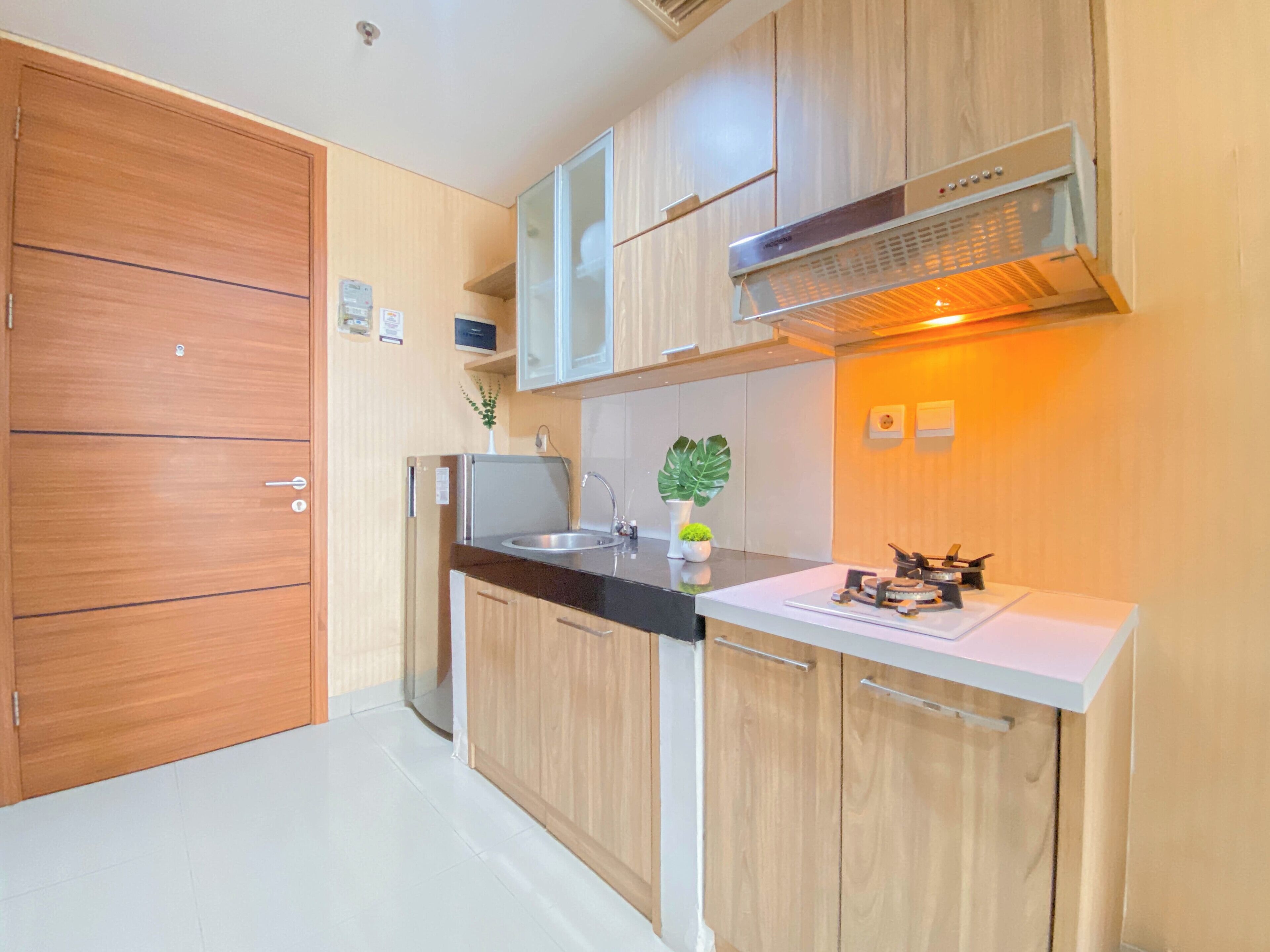 Una cocina moderna con armarios de madera, un refrigerador de acero inoxidable, un horno empotrado y una campana extractora.