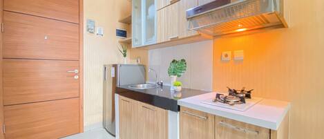Una cocina moderna con armarios de madera, un refrigerador de acero inoxidable, un horno empotrado y una campana extractora.