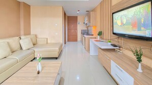 Een moderne woonkamer met een beige bank, een houten salontafel en een televisie bevestigd aan een houten wand.