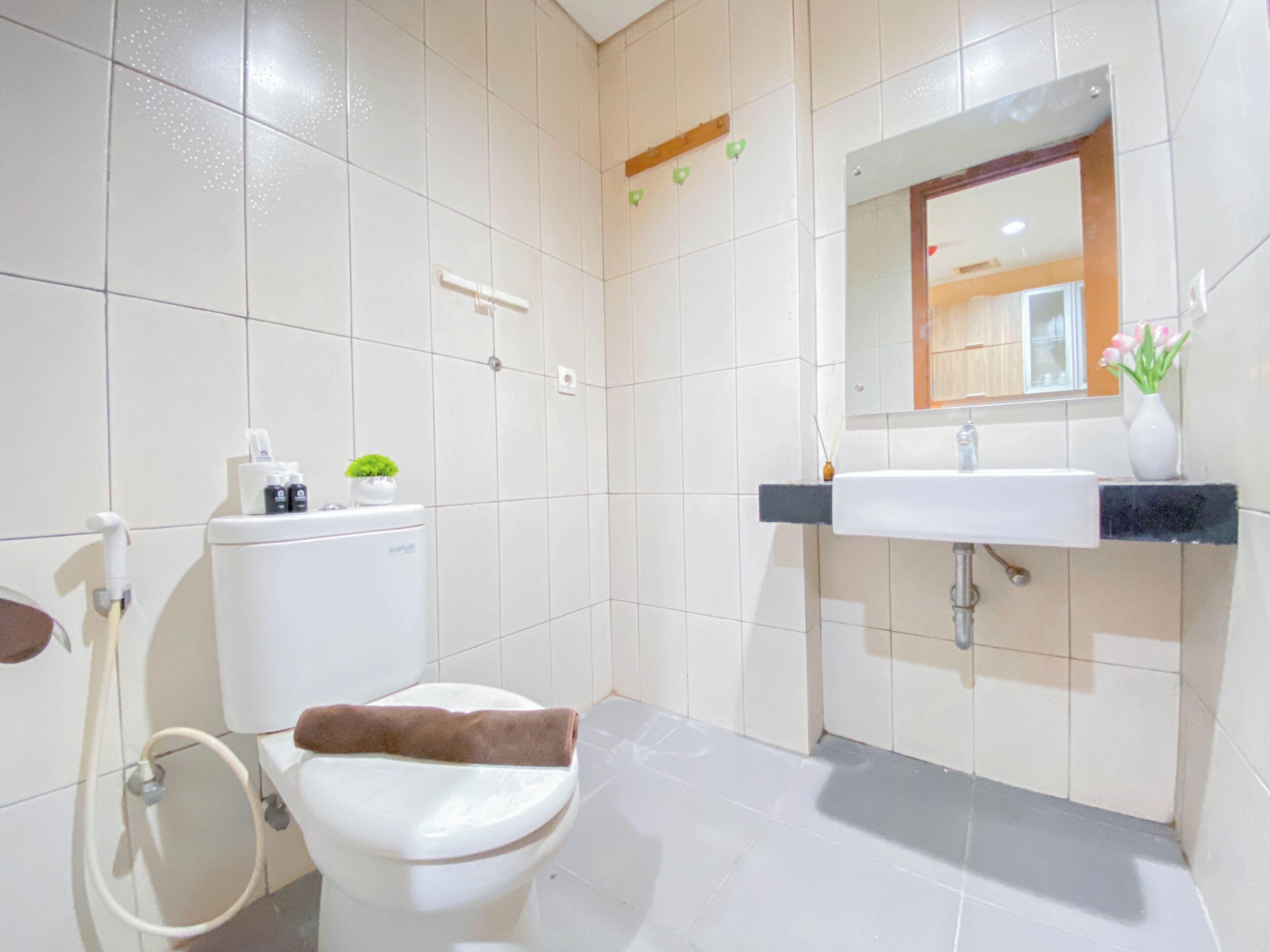 A bathroom with a toilet, sink, mirror, and a towel on the seat.