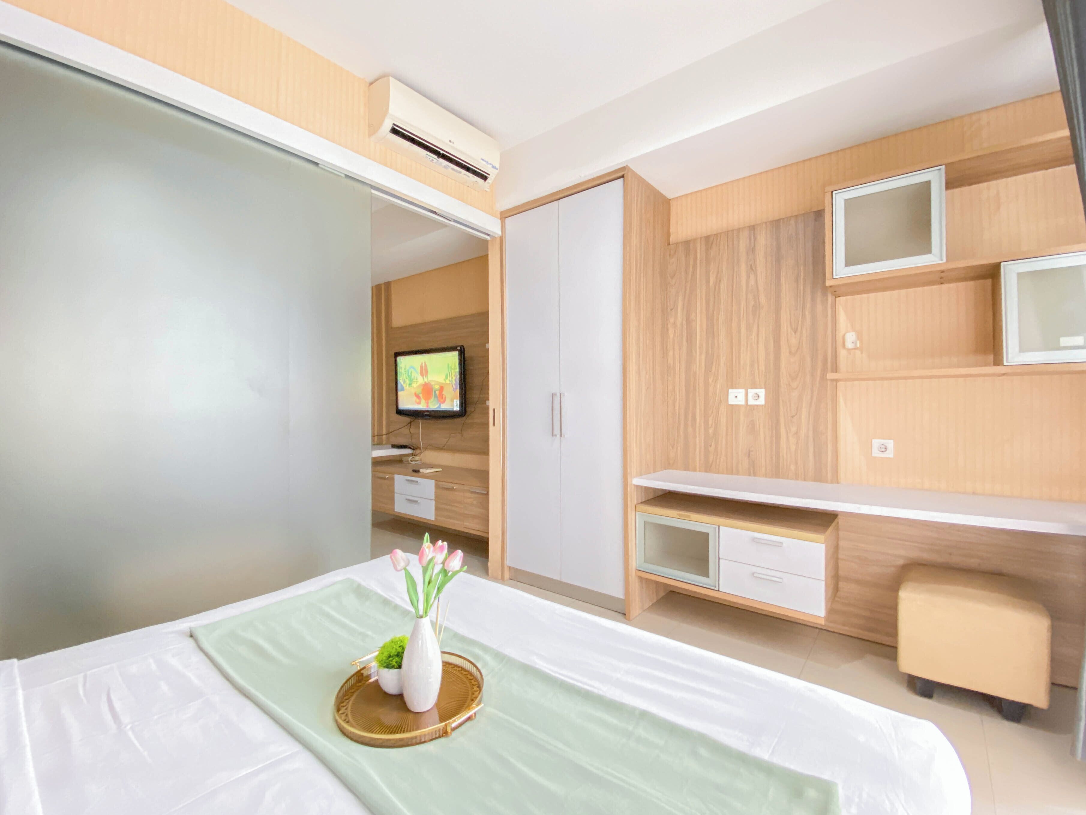 A hotel room with a bed, a desk, a TV, and a wardrobe.