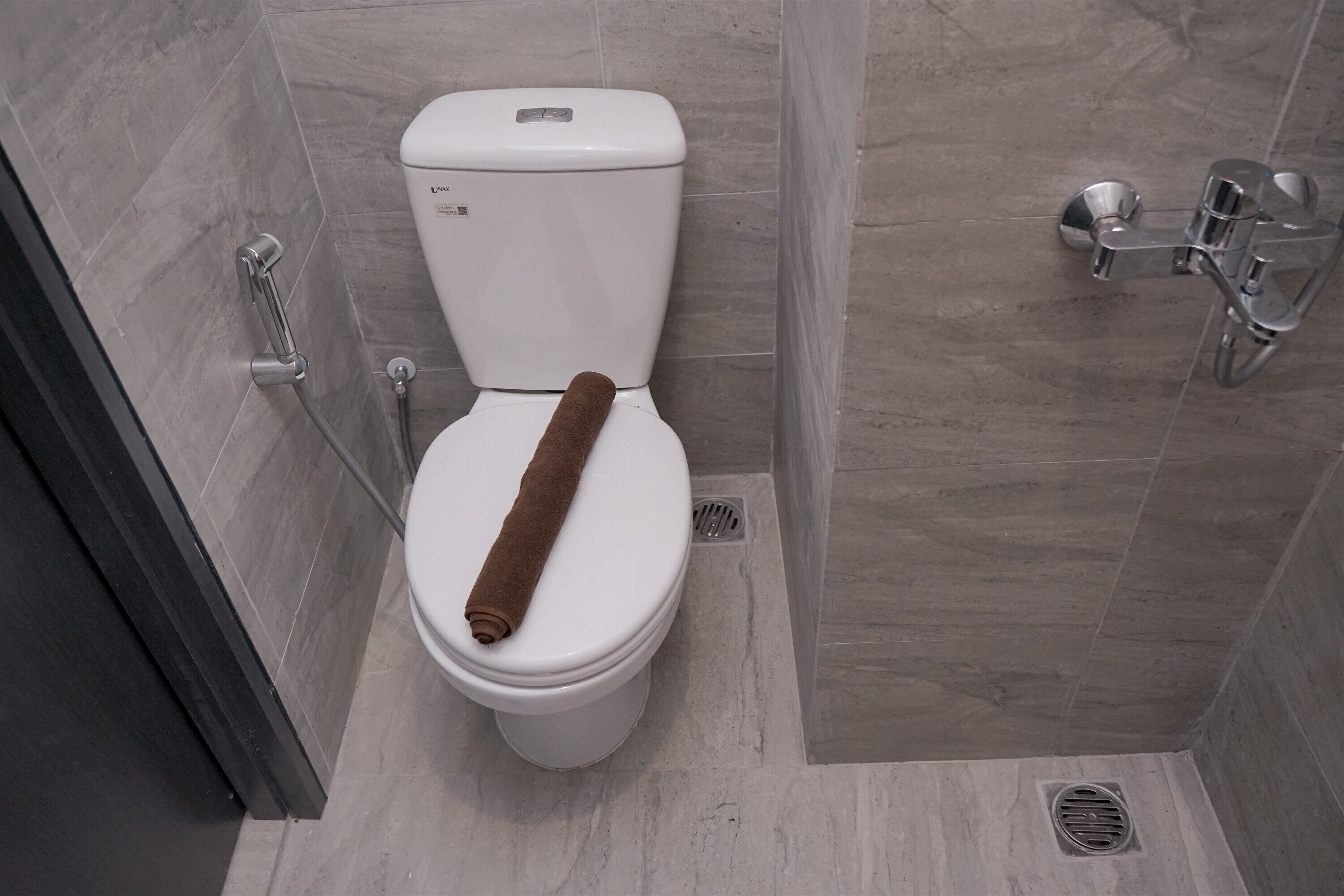 A modern bathroom with a white toilet, a shower area, and a towel rack.