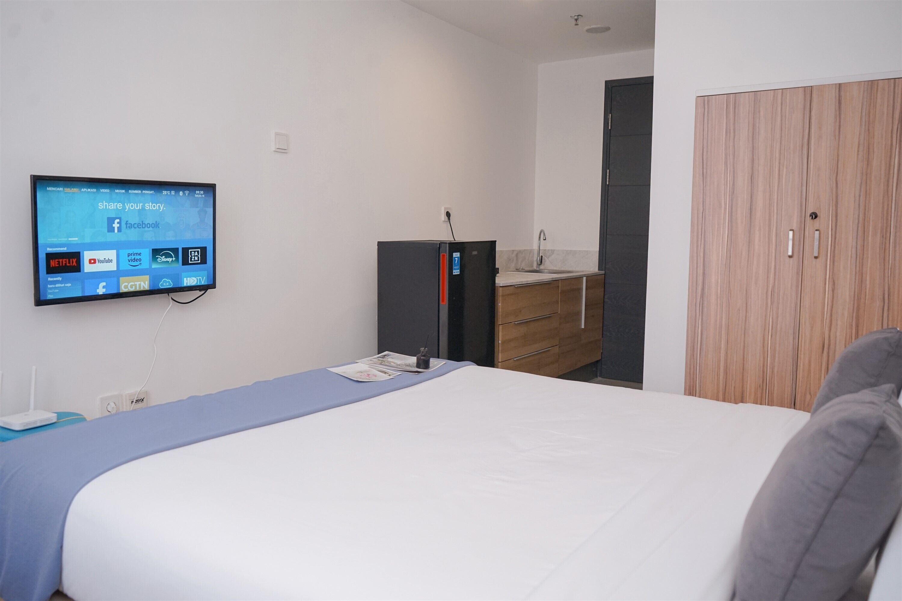Une chambre d’hôtel comprenant un lit, un téléviseur fixé au mur permettant d’accéder à des services de diffusion en continu, une armoire et un petit bureau avec une lampe.