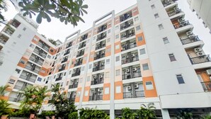 Un edificio residencial de varios pisos con balcones, piscina y zonas verdes circundantes.