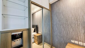 Una habitación de hotel moderna con armario, mesita de noche y espejo incorporado.