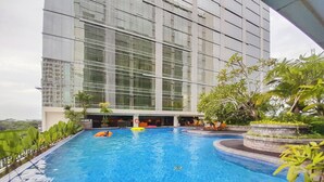 Una piscina con vista a un edificio moderno con grandes ventanales.