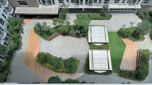 Μια αεροφωτογραφία ενός εσωτερικού χώρου με ένα κεντρικό, ανοιχτό σημείο, που περιβάλλεται από πράσινο και σύγχρονα κτίρια.