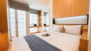 Une chambre d’hôtel avec un grand lit, une table de chevet, un miroir et une vue sur la ville par la fenêtre.