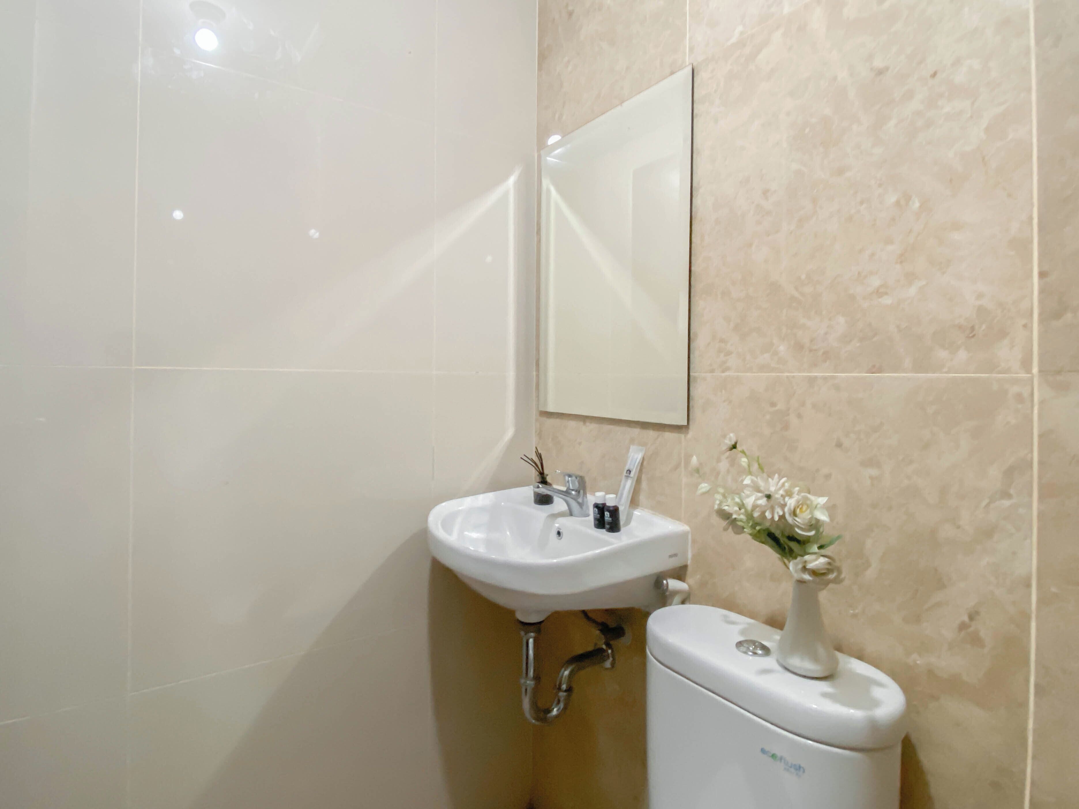 Un baño con lavamanos, espejo y retrete blanco.