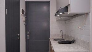 Une cuisine de taille réduite avec une porte sombre, un évier et un plan de travail.