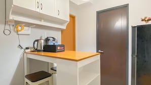 A compact kitchenette with a countertop, a kettle, a coffee maker, and a travel bag. - Cozy 1BR without Living Room at Royal Heights Apartment (Bogor)