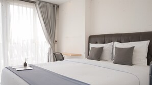 A hotel room with a large bed, a wooden nightstand, and a chair.
