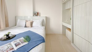 A neatly arranged bedroom with a bed, a bedside table with a plant, and a magazine. - Best Deal and Modern Style 2BR Apartment Bassura City (Jakarta)
