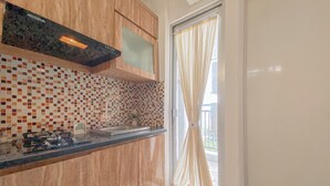 A modern kitchen with wooden cabinets, a tiled backsplash, and a stainless steel sink. - Best Deal and Modern Style 2BR Apartment Bassura City (Jakarta)