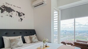 Ein Schlafzimmer mit einem großen Bett, einer Weltkarte an der Wand und Blick auf die Stadt durch das Fenster.