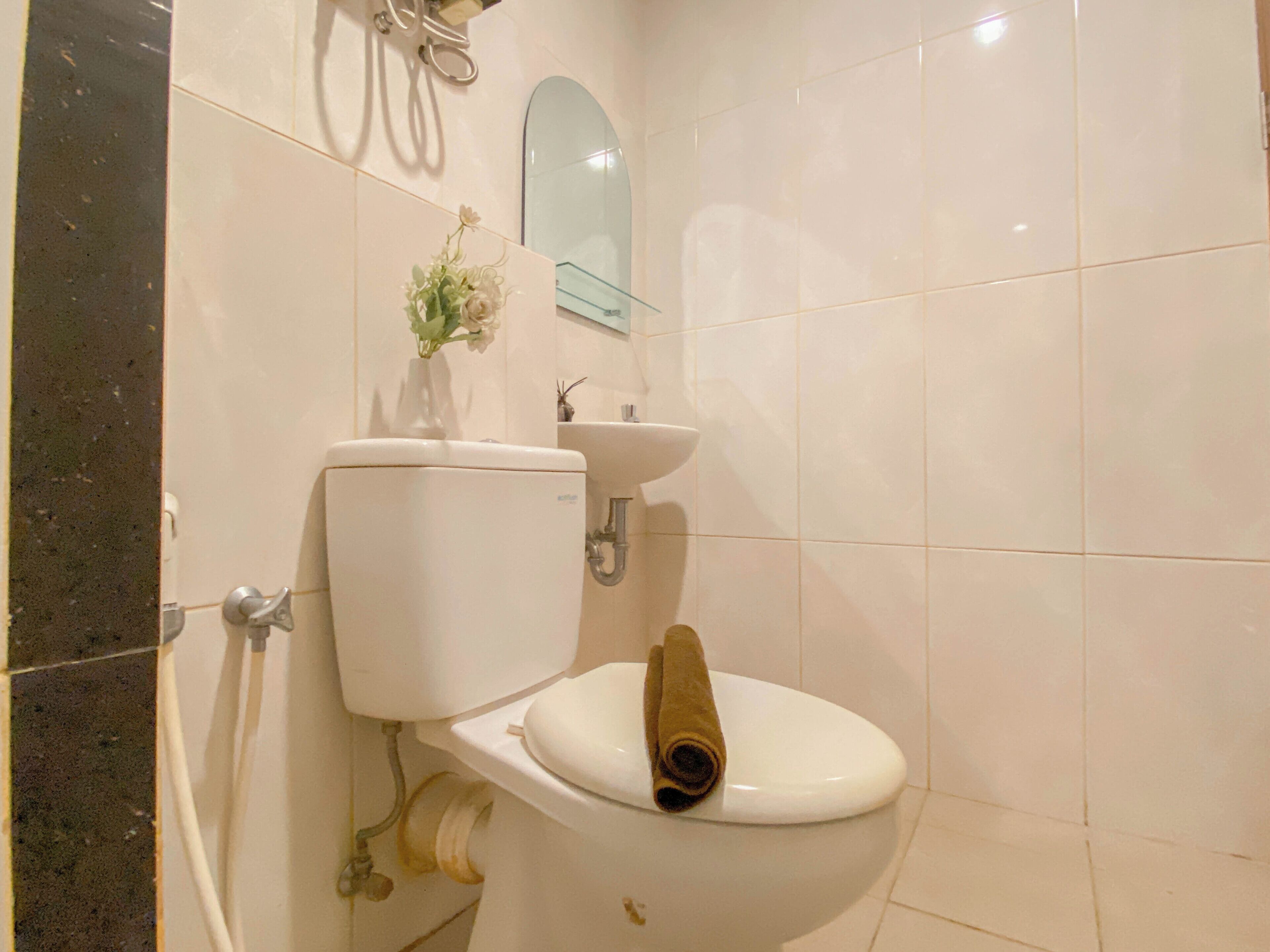 A bathroom with a toilet, sink, and mirror.