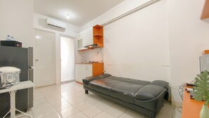 A compact living space with a kitchenette, a sofa, and a small table. - Comfy 1BR Apartment with Extra Room at Green Pramuka City near Mall (Jakarta)