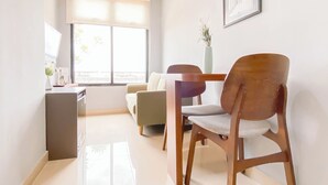 Ein modernes Wohnzimmer mit Essbereich, ausgestattet mit einer Couch, einem Holztisch und einem Stuhl.