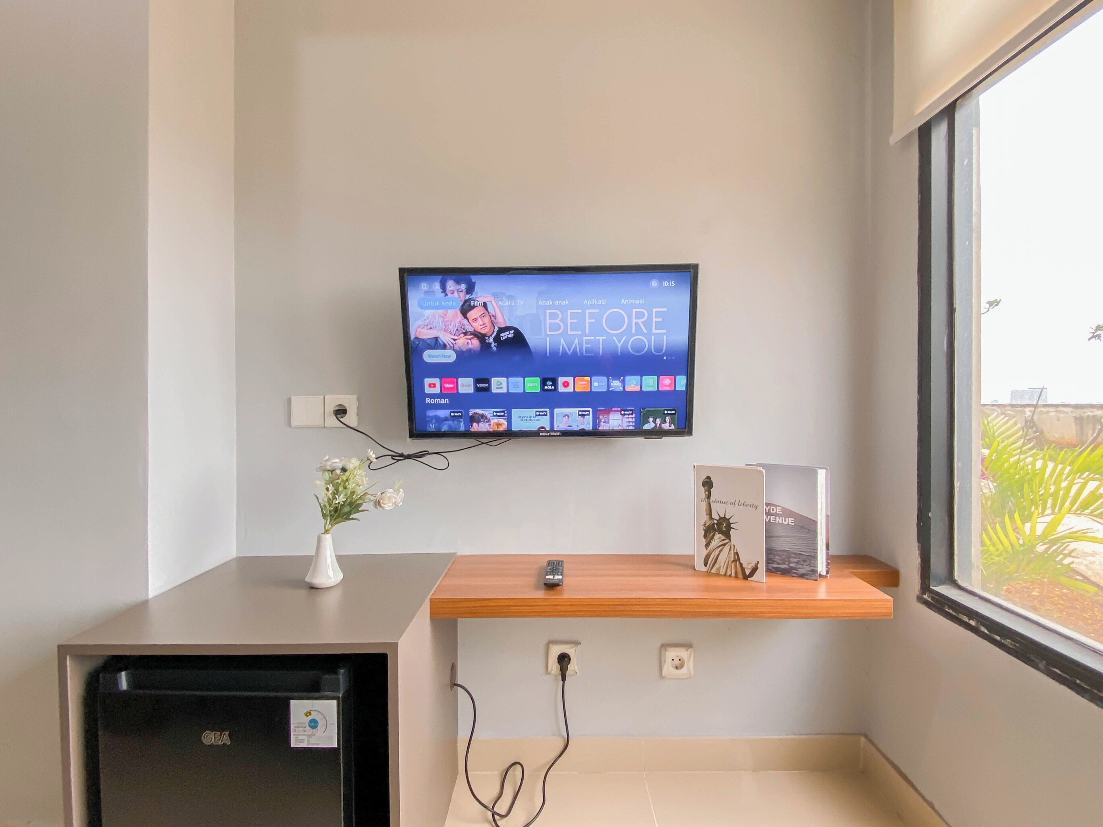 A television mounted on a wall displaying a movie with the title 'BEFORE MET YOU.'
