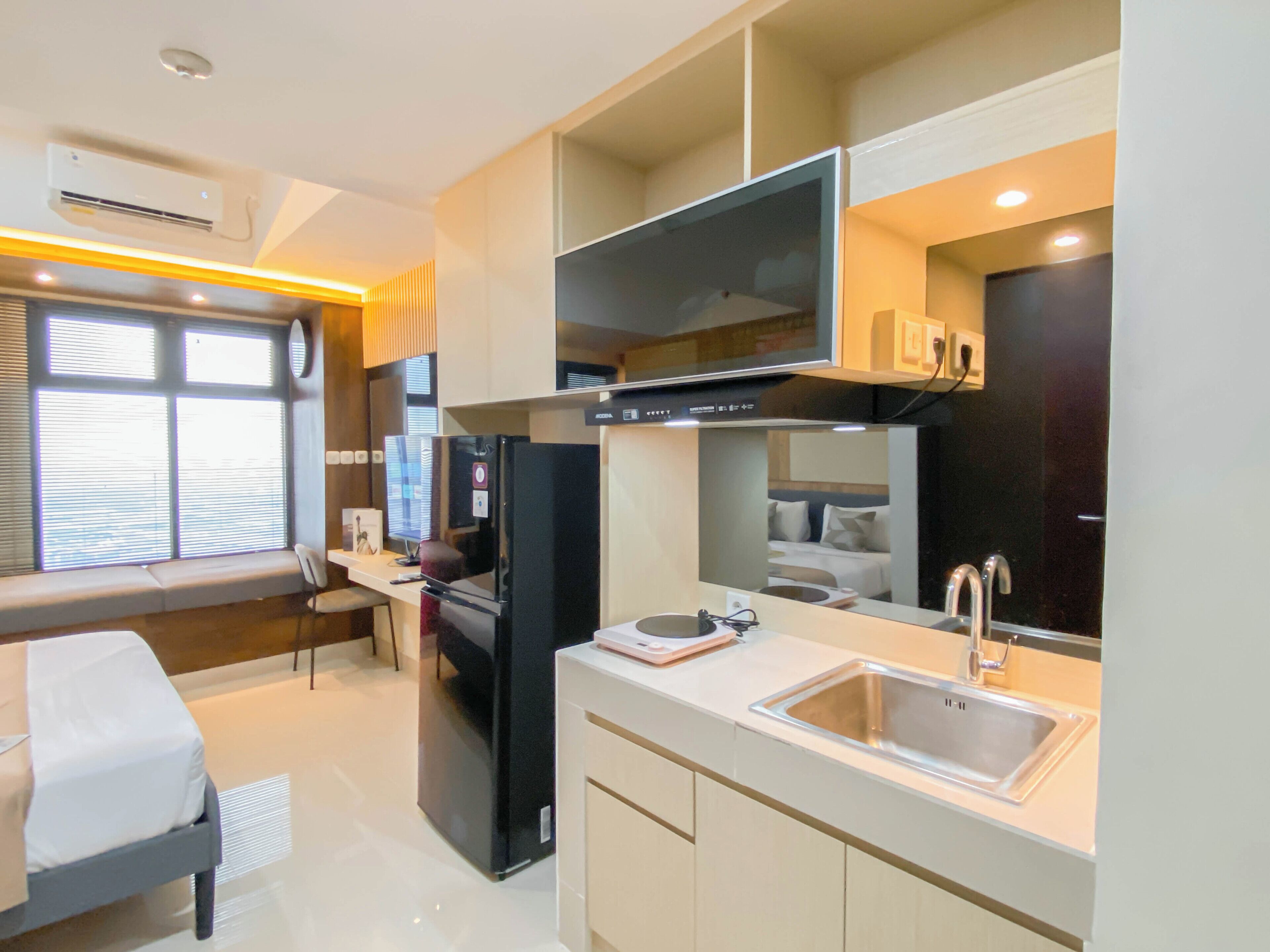 A modern kitchen with a built-in refrigerator, a microwave, and a large window with blinds.