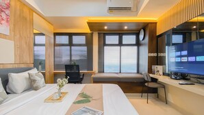 Ein modernes Hotelzimmer mit einem großen Bett, einem Schreibtisch mit Computer und einem Fenster mit Jalousien.