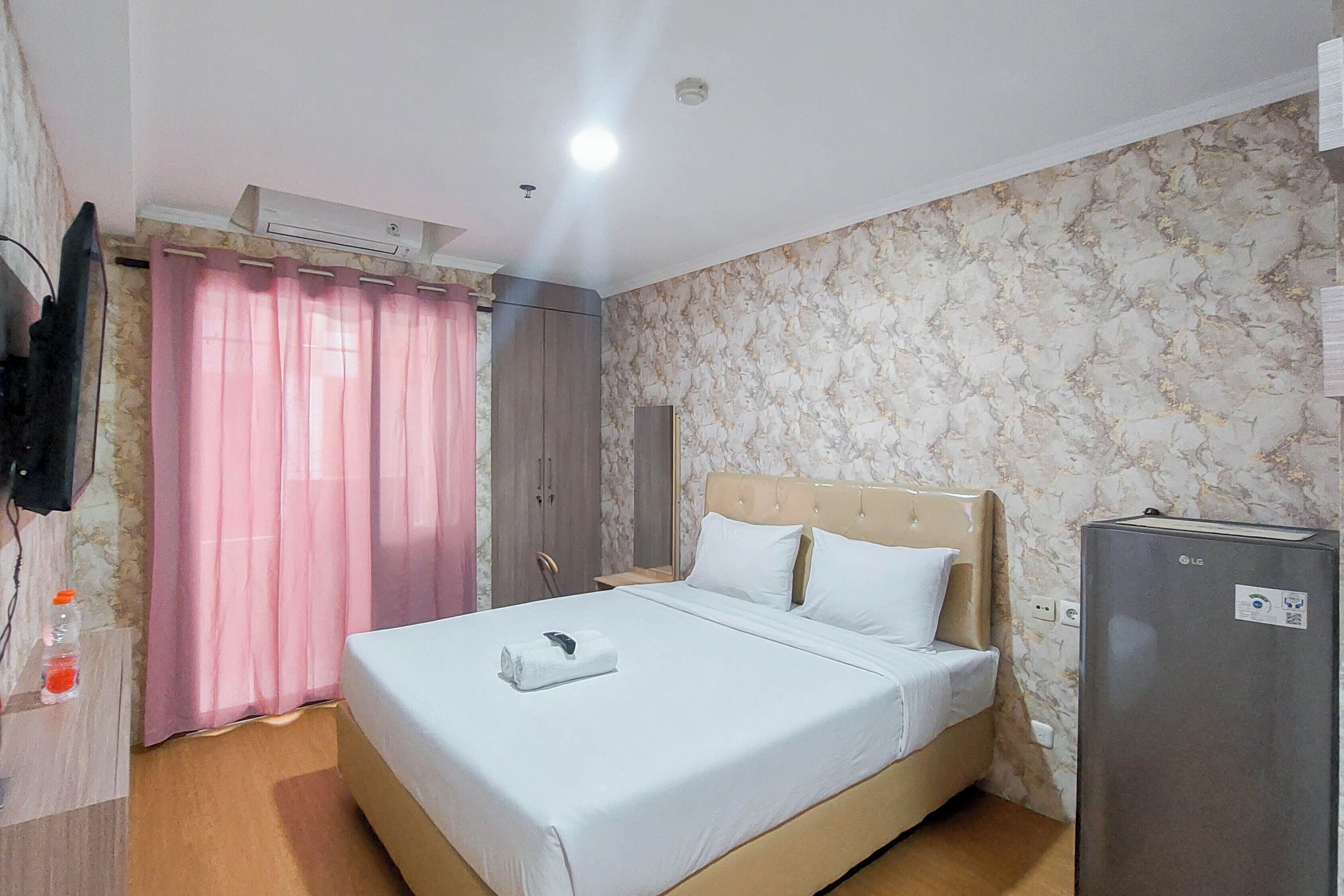 A hotel room with a bed, a wardrobe, a television, and a refrigerator.
