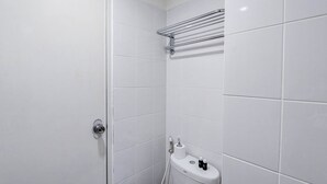 Une salle de bain avec des carreaux blancs, des toilettes, un porte-serviettes et une porte.