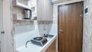 Une cuisine compacte équipée d’une cuisinière à gaz intégrée, d’un évier et d’une porte en bois.