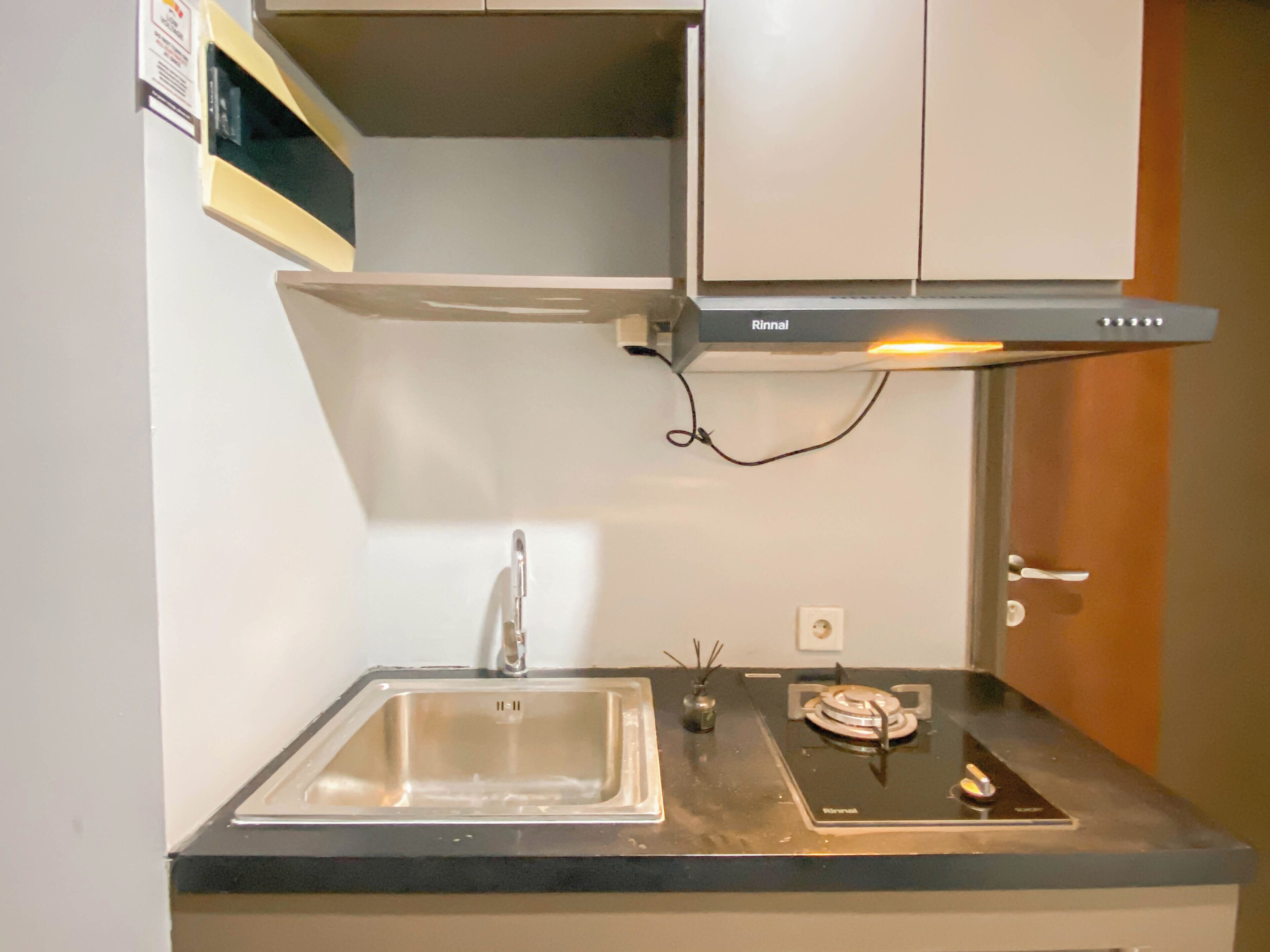 Una cucina compatta con lavandino, fornello e microonde.