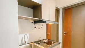 A compact kitchen with a stainless steel sink, a built-in stove, and a black range hood. - Simply Look And Best Deal 2BR at Pollux Chadstone Apartment (Cikarang)