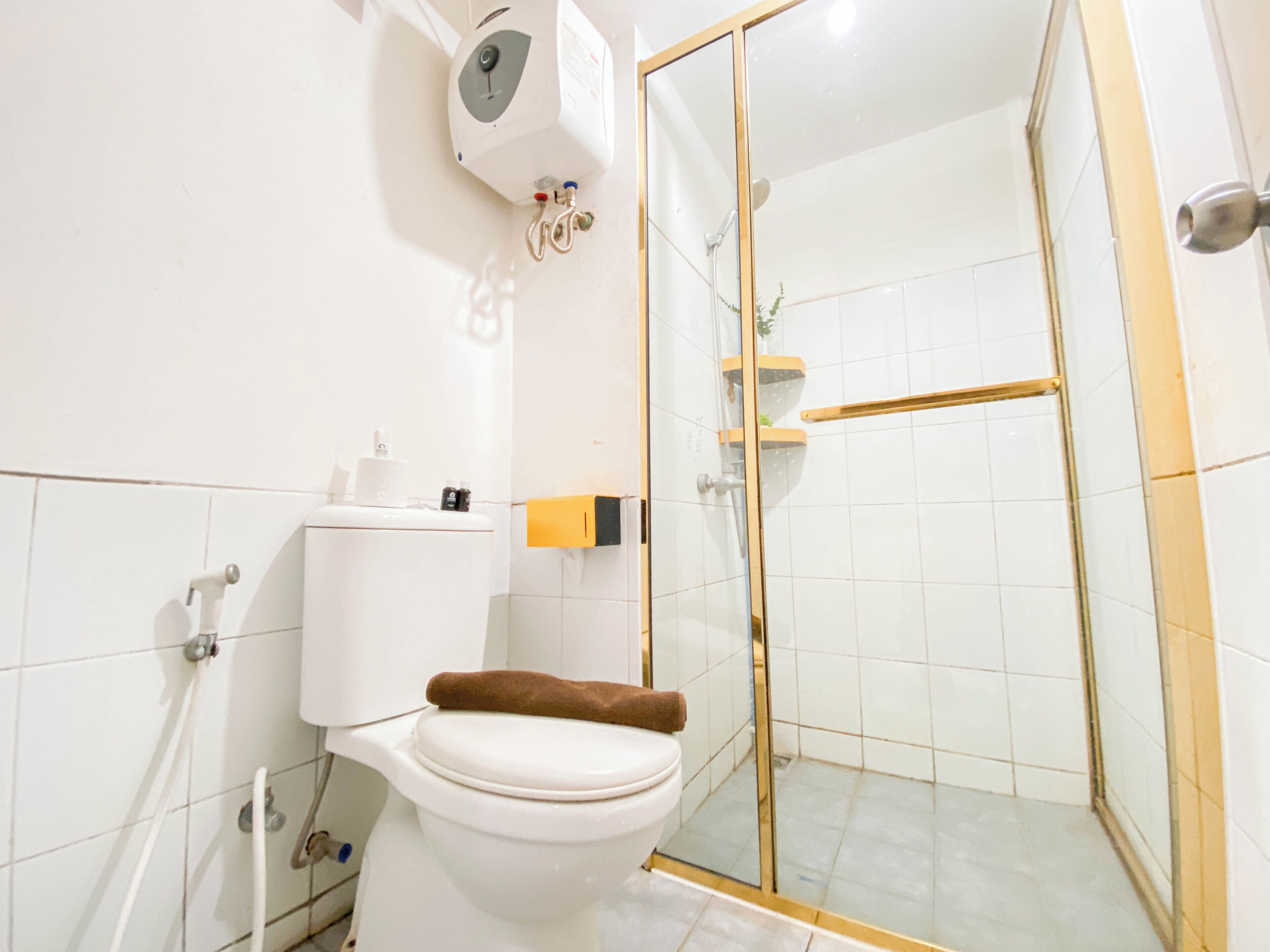 A bathroom with a toilet, a glass-enclosed shower, and a white tiled wall.