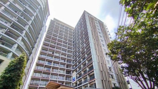 A multi-story hotel with a modern architectural design, featuring a prominent entrance with a covered area and visible signage. - Homey Studio Apartment at Beverly Dago (Bandung)