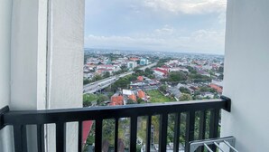 Un balcón con vista a un paisaje urbano, que incluye edificios y una autopista.