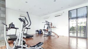 Un gimnasio espacioso con máquinas de cardio, equipo de levantamiento de pesas y un amplio ventanal con vistas al exterior.