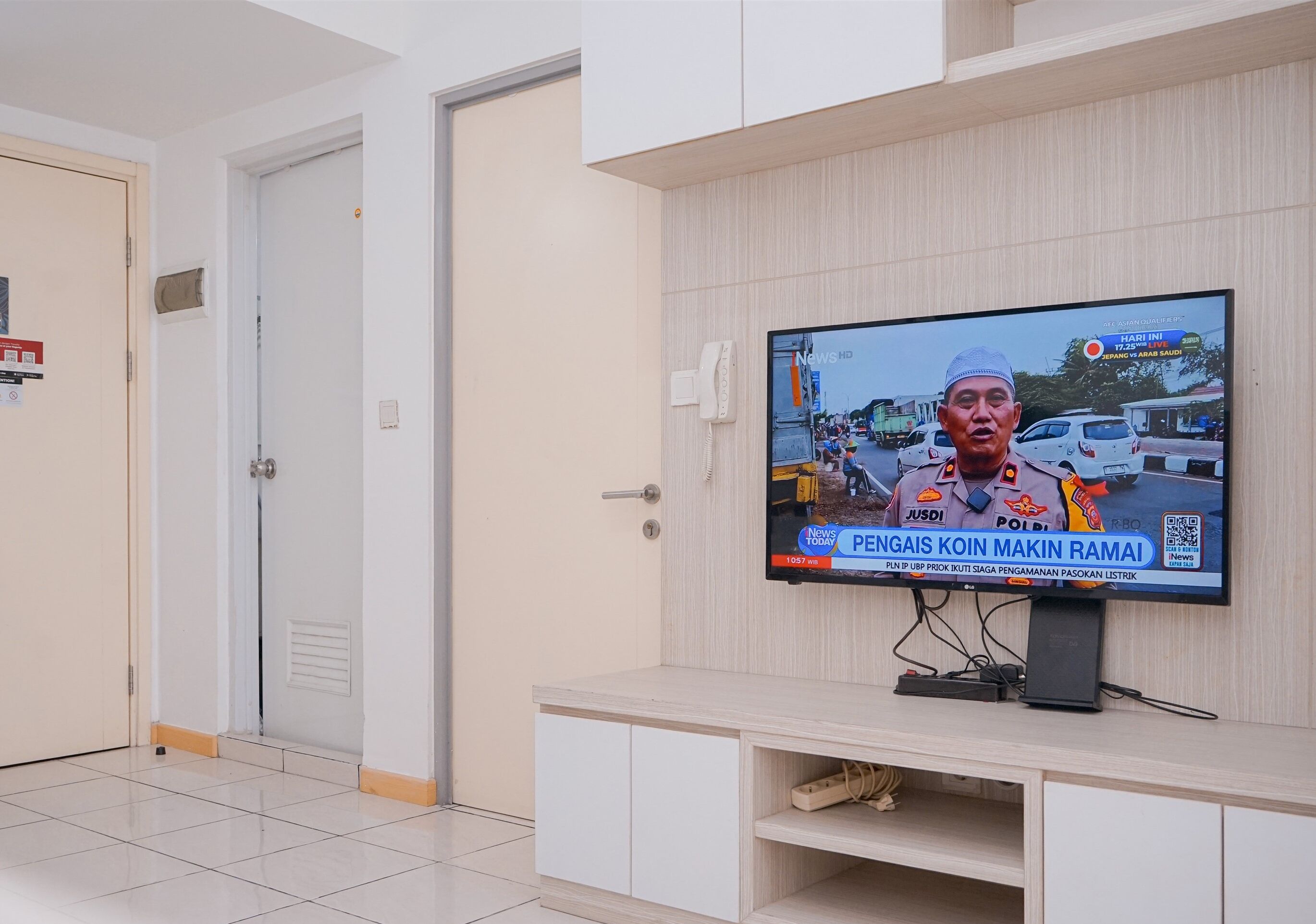 A television mounted on a wall displaying a news broadcast.