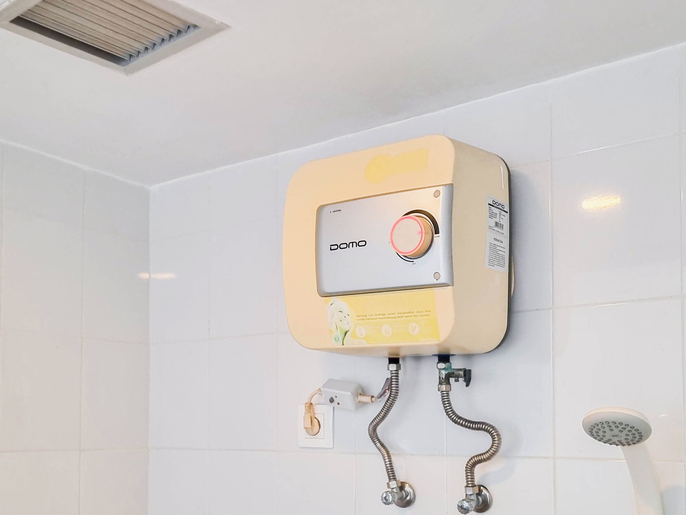 A bathroom with a wall-mounted DOOMA water heater, a showerhead, and a ventilation grille.
