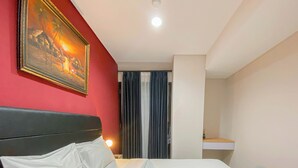 Ein Hotelzimmer mit einem Bett, einem Bild an der Wand und einem Fenster mit Vorhängen.