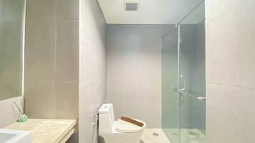 Un baño con inodoro, cabina de ducha de cristal y bañera.